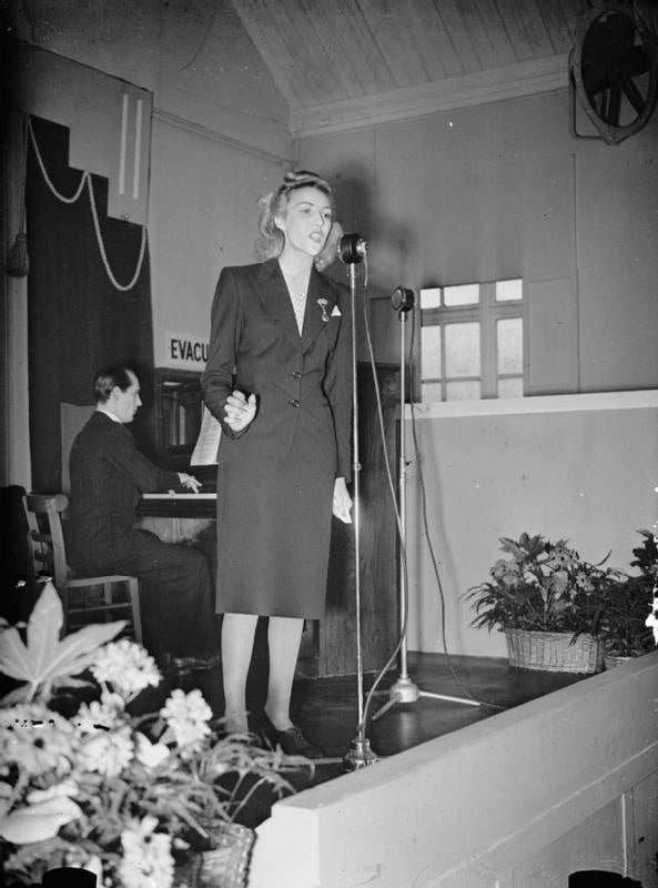 Vera Lynn sings to workers during a lunchtime concert at a munitions factory, 1941. WC PD.