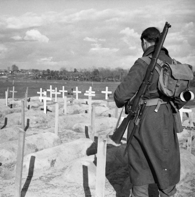 Private Phillip Johnson of the 2/6th Queen's Regiment inspects British graves at Anzio, 1 March 1944. WC PD.